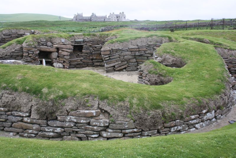 In der Jungsteinzeit war das Klima zwar etwas freundlicher zum Norden Schottlands, aber schon damals war es eine gute Idee, die Häuser halb in den Erdboden zu bauen und damit zu isolieren. Im Hintergrund ist Skraill House zu sehen, das ebenfalls besichtigt werden kann. 